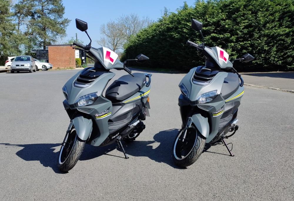 two mopeds lined up in a  car park